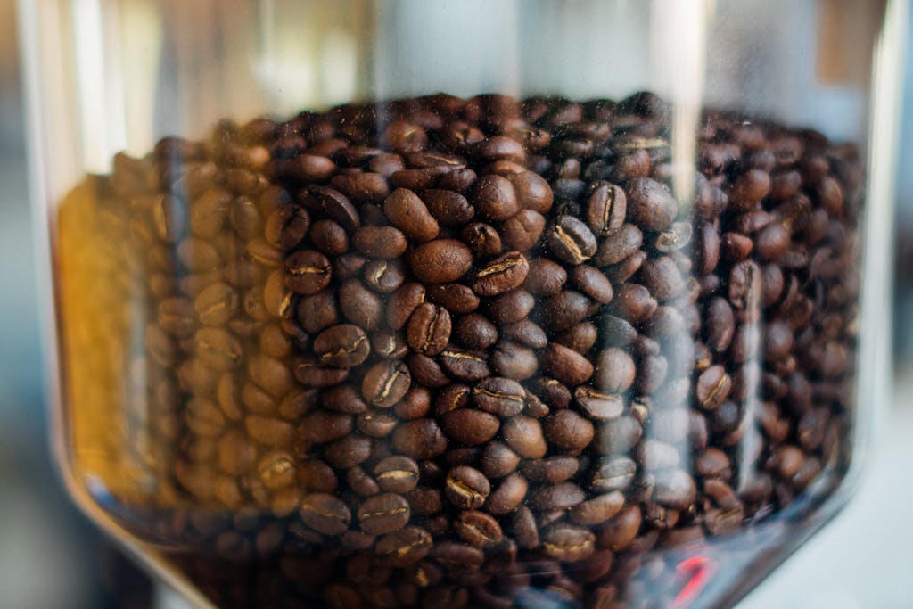 Aromatic roasted coffee beans stored in a clear glass jar, showcasing rich textures.